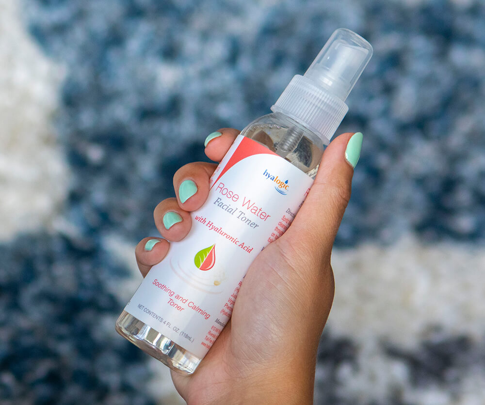 Hyalogic Rose Water facial toner with hyaluronic acid held in hand for soothing and hydrating skin at Modern Radiance Oregon.